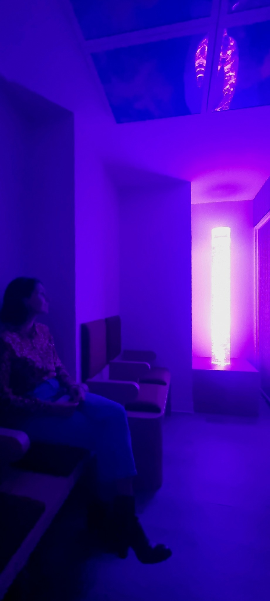 Personne installée face à une colonne à bulles dans un espace sensoriel du service d’oncologie